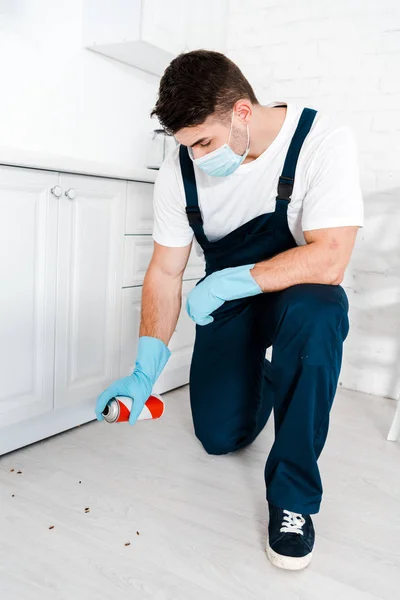 Exterminateur en gants de latex bleu tenant pulvérisation peut près des insectes sur le sol — Photo de stock