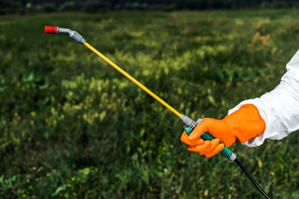 Cropped view of exterminator in latex glove holding spray outside — Stock Photo