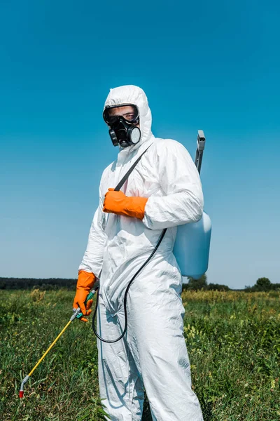 Exterminator in white uniform and latex gloves holding spray against sky — Stock Photo