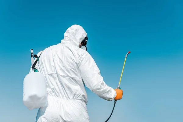 Kammerjäger in weißer Schutzuniform hält Giftspray draußen — Stockfoto