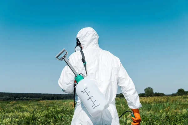 Exterminador en uniforme blanco con spray tóxico exterior - foto de stock
