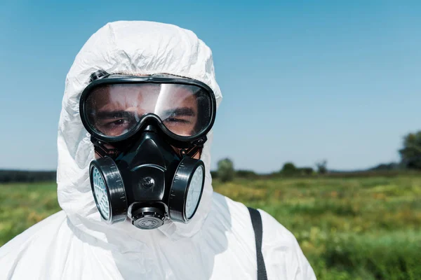 Exterminateur en uniforme et masque protecteur regardant la caméra contre le ciel — Photo de stock