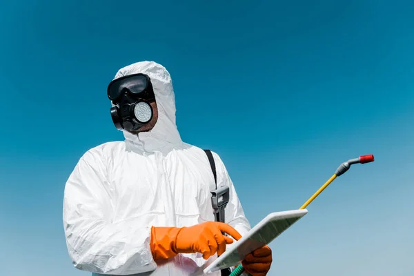 Hombre en máscara protectora y uniforme apuntando con el dedo a la tableta digital - foto de stock