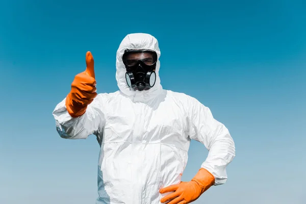 Exterminator in protective mask and uniform standing with hand on hip and showing thumb up — Stock Photo