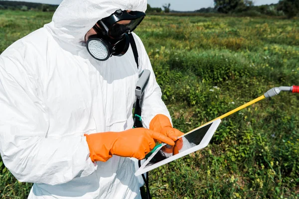 Exterminator in protective mask and uniform pointing with finger at laptop — Stock Photo