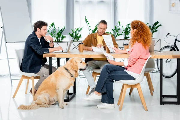 Trois amis assis à table et faisant de la paperasserie au bureau — Photo de stock