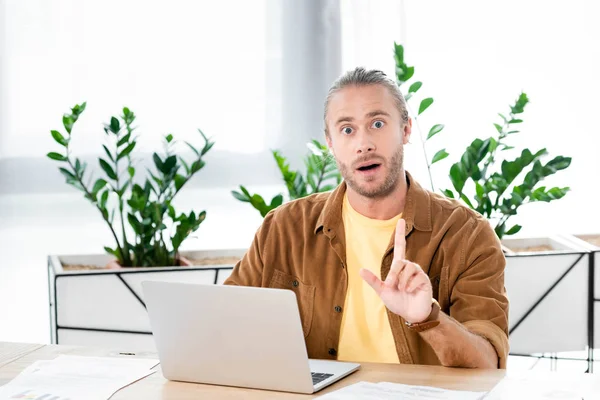 Handsome and shocked businessman showing idea sign in office — Stock Photo