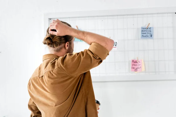 Back view of man in shirt looking at white board in office — Stock Photo