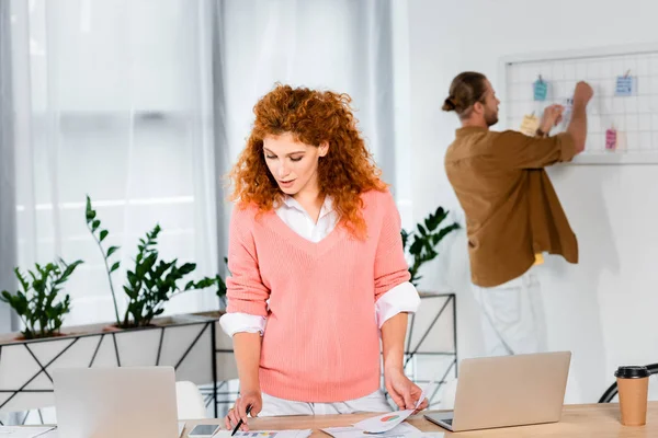 Selektiver Fokus der attraktiven Geschäftsfrau im rosa Pullover, die im Büro Papierkram erledigt — Stockfoto