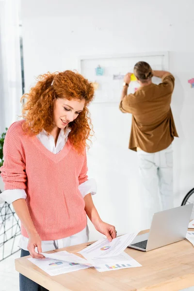 Selektiver Fokus der attraktiven Geschäftsfrau im rosa Pullover, die im Büro Papierkram erledigt — Stockfoto