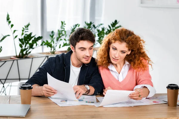 Two smiling friends doing paperwork and sitting at table in office — Stock Photo