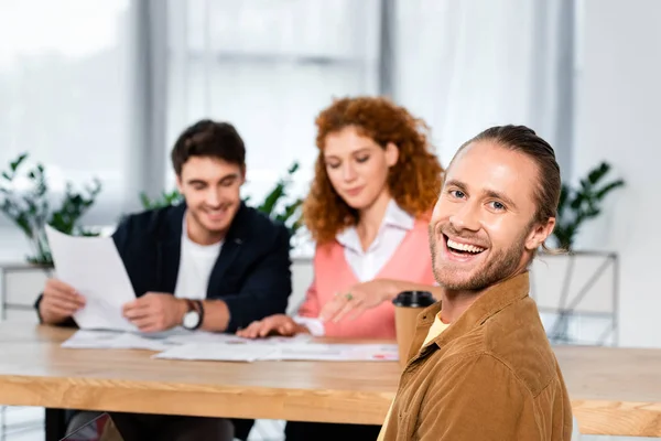 Selektiver Fokus eines gut aussehenden und lächelnden Mannes, der in die Kamera blickt — Stockfoto