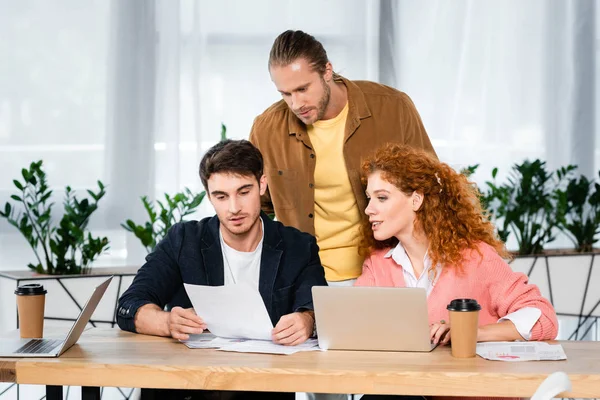 Drei Freunde erledigen Papierkram und sitzen am Tisch im Büro — Stockfoto