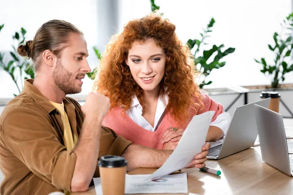 Zwei lächelnde Freunde sitzen am Tisch und erledigen im Büro Papierkram — Stockfoto