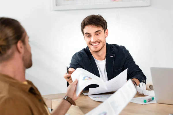 Foyer sélectif de l'homme en chemise donnant du papier à son ami souriant au bureau — Photo de stock