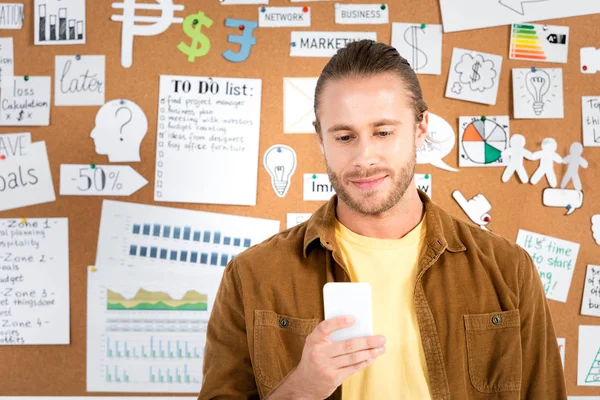 Schöner Geschäftsmann im braunen Hemd mit Smartphone im Büro — Stockfoto