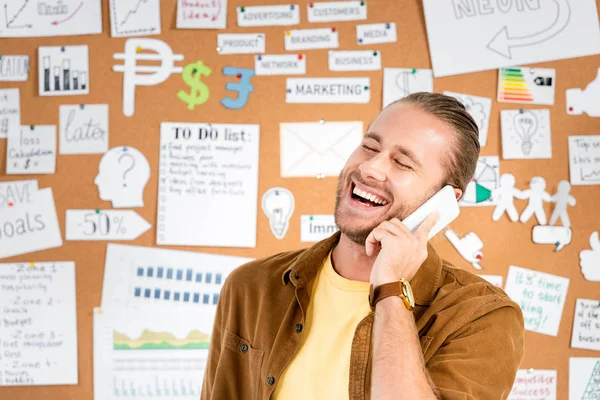 Gutaussehender und lächelnder Geschäftsmann, der im Büro mit dem Smartphone spricht — Stockfoto
