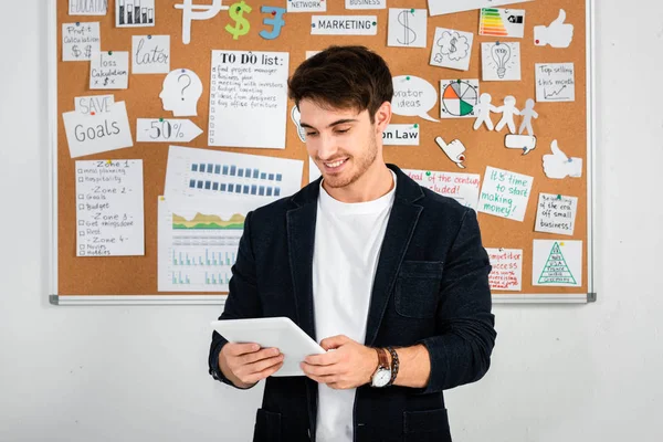 Homem de negócios sorridente e bonito na camisa usando tablet digital no escritório — Fotografia de Stock