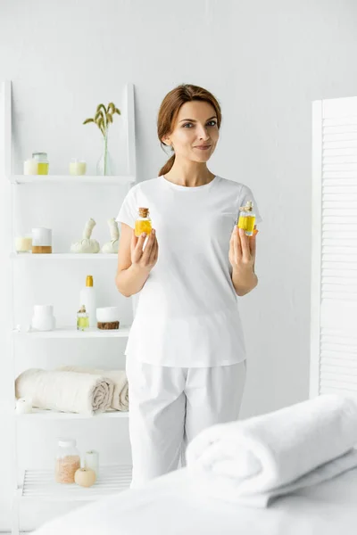 Attractive masseur holding fragrance oils in bottles in spa — Stock Photo