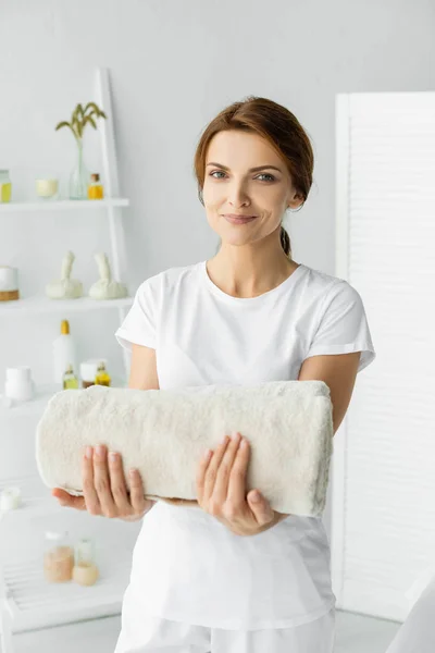 Massagista atraente segurando toalha branca e olhando para a câmera — Fotografia de Stock