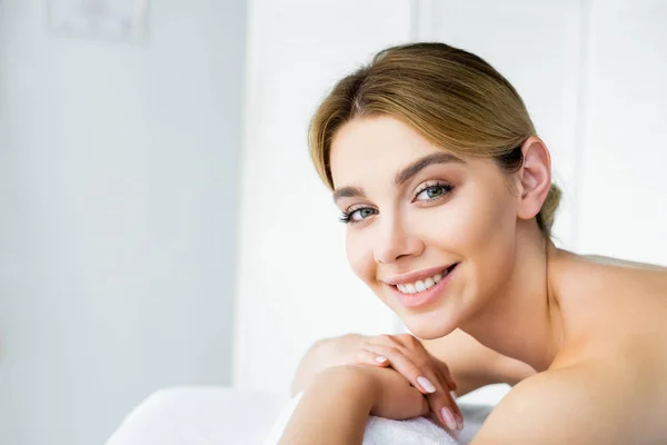 Mulher atraente e sorridente deitado no tapete de massagem no spa — Fotografia de Stock