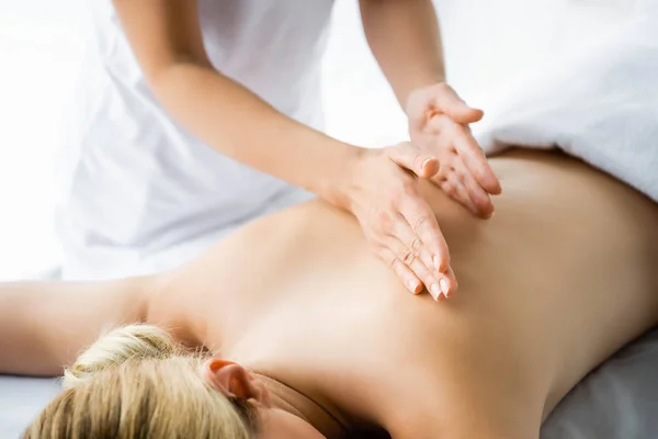 Cropped view of masseur doing back massage to woman in spa — Stock Photo