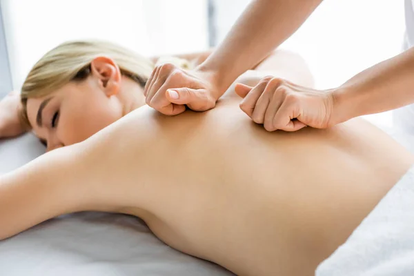 Vista ritagliata di massaggiatore facendo massaggio alla schiena alla donna in spa — Foto stock