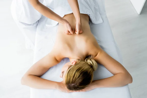 Recortado vista de masajista haciendo masaje de espalda a mujer en spa - foto de stock