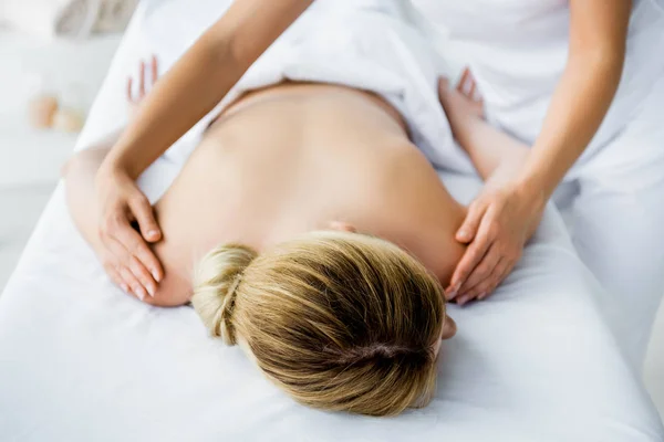 Recortado vista de masajista haciendo masaje de espalda a mujer en spa - foto de stock