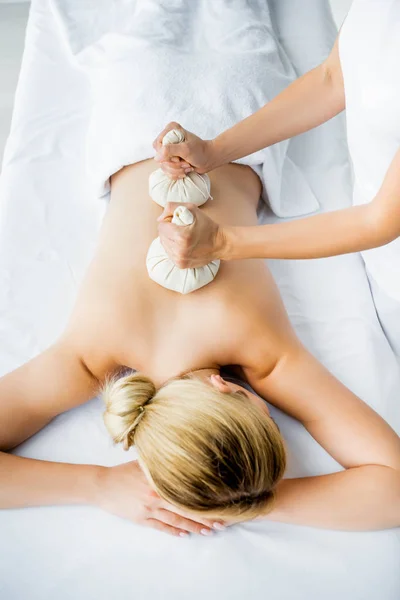 Ausgeschnittene Ansicht des Masseurs bei einer Rückenmassage mit Kräuterbällen für die Frau im Spa — Stockfoto