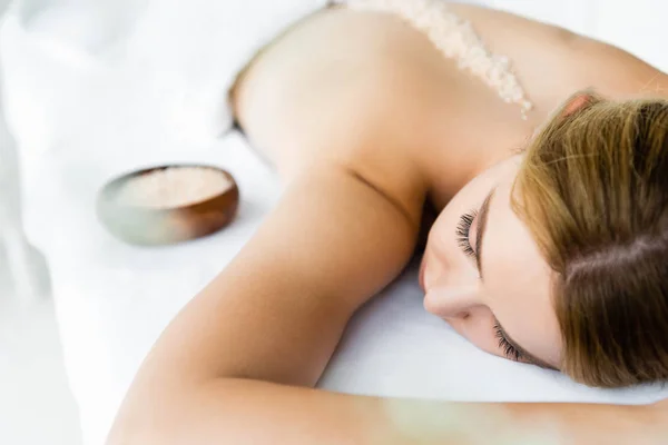 Selective focus of woman lying on massage mat with sea salt on back — Stock Photo