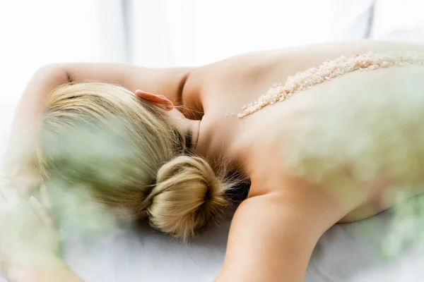 Жінка лежить на масажному килимку з морською сіллю на спині — стокове фото