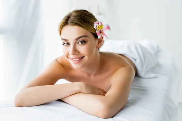 Приваблива і усміхнена жінка з квіткою, що лежить на масажному килимку — стокове фото