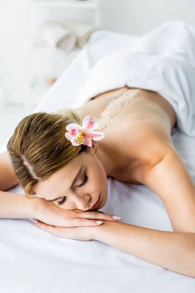 Vista ad alto angolo di donna attraente con fiore sdraiato sul tappetino da massaggio — Foto stock