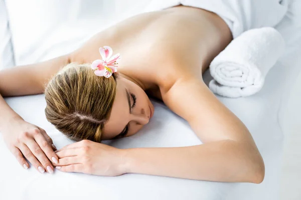 High angle view of attractive woman with flower lying on massage mat — Stock Photo