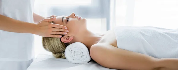 Panoramic shot of masseur doing face massage to attractive woman — Stock Photo