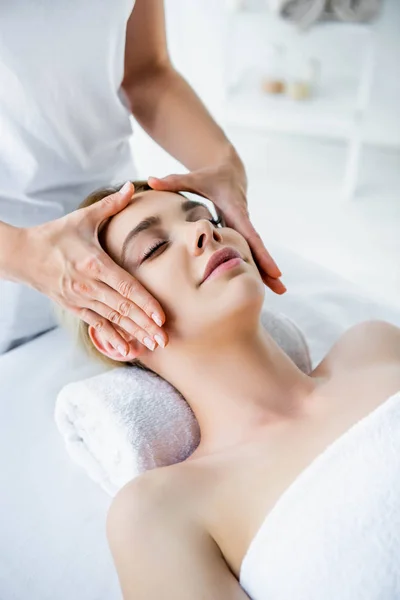 Vista ritagliata di massaggiatore facendo massaggio viso alla donna attraente — Foto stock