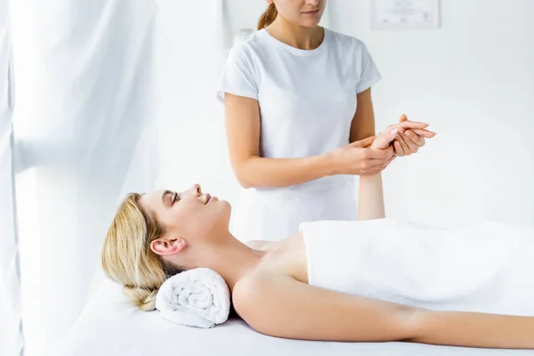 Vista cortada de massagista fazendo massagem de mão para mulher atraente — Fotografia de Stock