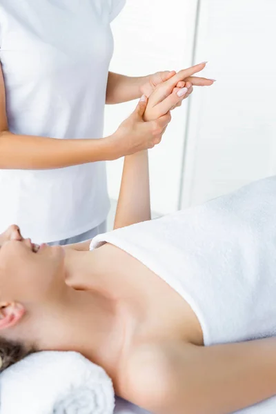 Recortado vista de masajista haciendo masaje de manos a la mujer sonriente - foto de stock