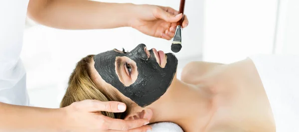 Panoramic shot of beautician applying clay mask on face of woman — Stock Photo