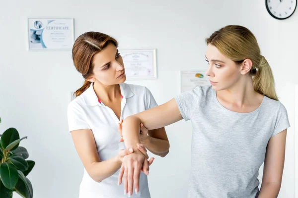 Chiropracteur toucher la main d'un patient attrayant en t-shirt gris — Photo de stock