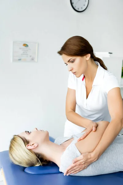 Chiropraktiker berührt Hand eines Patienten im grauen T-Shirt in Klinik — Stockfoto