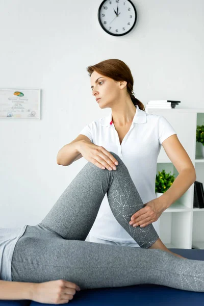 Ausgeschnittene Ansicht eines Chiropraktikers, der Bein einer Patientin in grauen Leggings berührt — Stockfoto