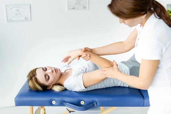 Chiropractor touching hand of attractive patient in grey t-shirt — Stock Photo