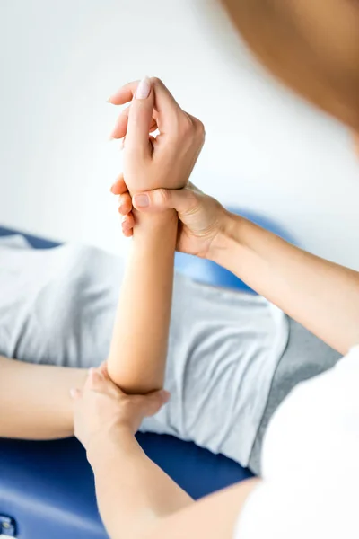 Vista recortada del quiropráctico tocando la mano del paciente en camiseta gris - foto de stock