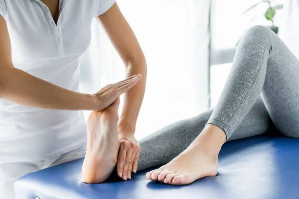 Cropped view of chiropractor touching foot of patient in clinic — Stock Photo