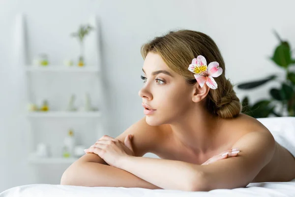 Attraktive Frau mit Blume liegt auf Massagematte im Wellnessbereich — Stockfoto