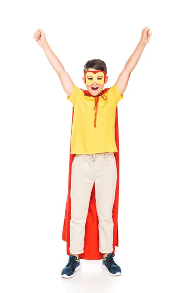 Full length view of smiling kid in mask and hero cloak showing yes gesture isolated on white — Stock Photo