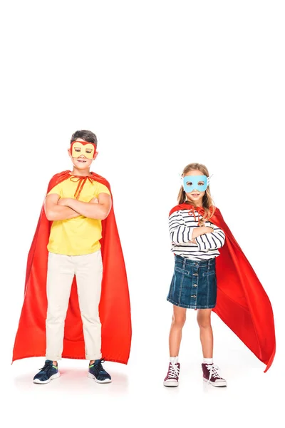 Full length view of two kids in hero cloaks standing with crossed arms on white — Stock Photo