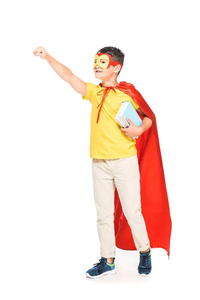 Full length view of kid in mask and hero cloak holding books isolated on white — Stock Photo